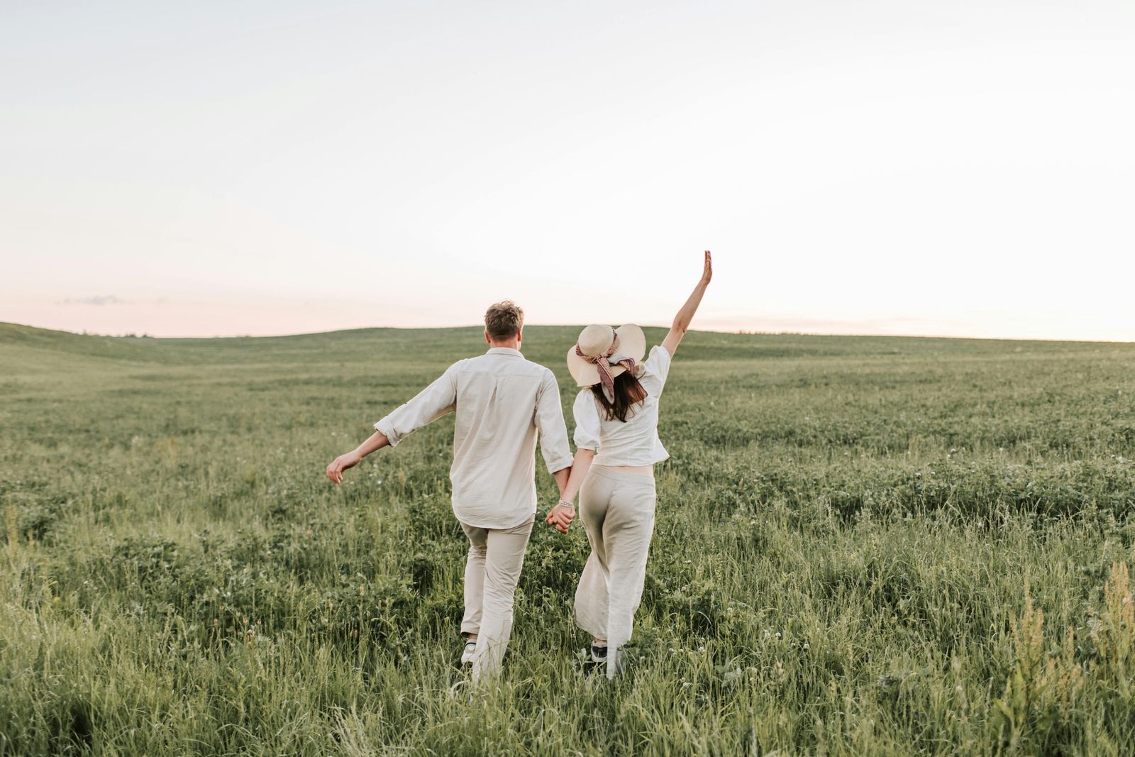 Couple at sunset walking through a field together